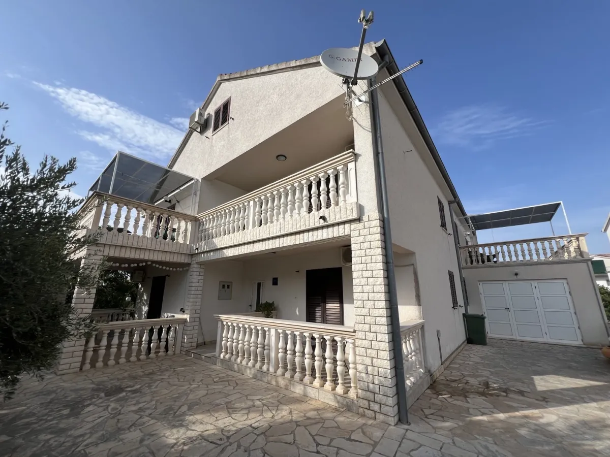 Die Villa Smokvica: weisses Haus mit Balustraden-Balkonen über drei Etagen, davor der gepflasterte Hof.